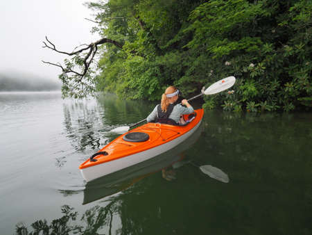 Lake Santeetlah, North Carolina June 6, 2018 Woman kayaks on Lake Santeetlah, North Carolina early on a foggy summer morning.のeditorial素材