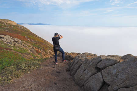 Point Reyes National Seashore, California 10-14-2015 Woman hikes and photographs the rugged landscape of Point Reyes in Northern California.のeditorial素材