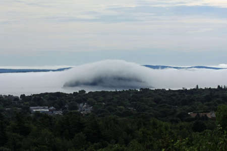 Dense fog rolling into Bar Harbor, Maine, covering islands in the distance in Frenchman Bay.