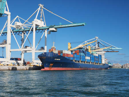 Miami, Florida 03-01-2019 Container ships load cargo containers under the gantry cranes of the Port of Miami on a clear winter afternoon.のeditorial素材