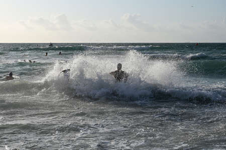 Miami Beach, Florida April 14, 2019 Male triathletes run into heavy surf at the start of the 2019 South Beach Triathlon.のeditorial素材