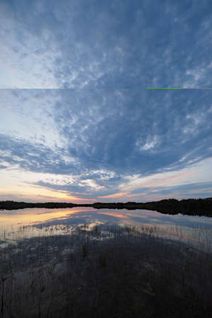 Sunrise clouds reflected on calm water of Nine Mile Pond in Everglades National Park, Florida.