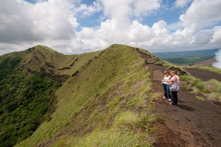 Masaya, Nicaragua - September 23, 2007: Two women view craters and gas emissions of Masaya Volcano from footpath near crater rim.のeditorial素材