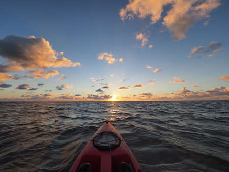 Red kayak pointing toward horizon at sunrise on windy morning in Bear Cur off Key Biscayne, Florida.の写真素材