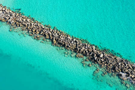 Aerial view of rock jetty of Government Cut surrounded by clear shallow water of Miami Beach, Florida on sunny summer morning.の写真素材