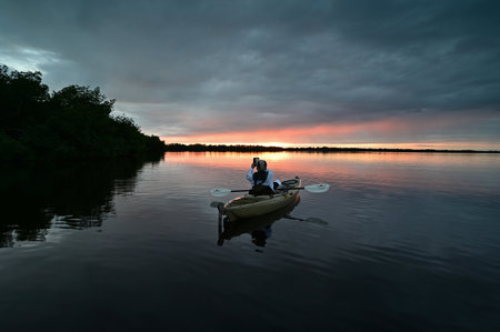 Everglades National Park, Florida - December 12, 2020 - Active senior kayaks at sunset under dramatic winter cloudscape in Coot Bay.のeditorial素材