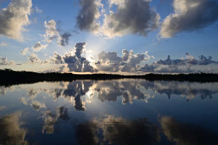 Colorful sunrise cloudscape reflected in calm water of Nine Mile Pond in Everglades National Park,...