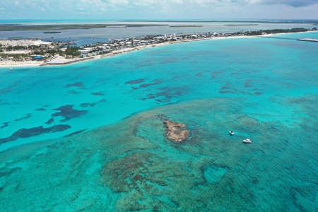 Aerial view of boats anchored near coral rocks with North Bimini coast in background on sunny summer...