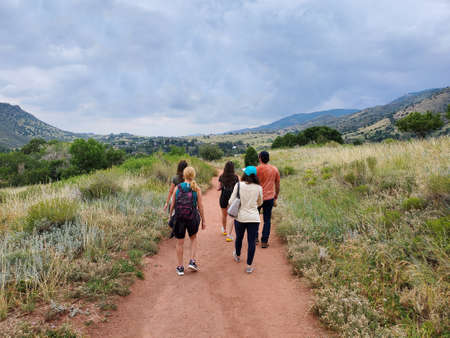 Five young hikers on Red Rocks Trading Post Trail near Morrison, Colorado under dramatic summer cloudscape.の写真素材