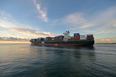 Miami Beach, Florida - September 25, 2021 - Container ship exits Government Cut at sunrise.