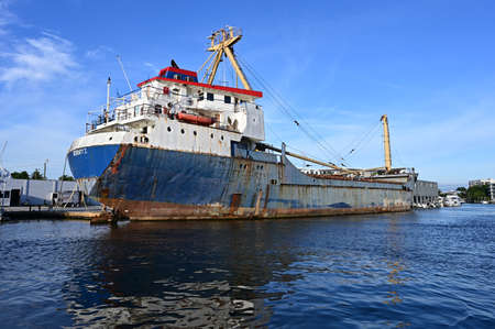 Miami, Florida - November 14, 2021 - Rusty cargo ship docked in Miami River on sunny autumn morning.