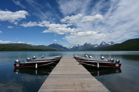 Apgar Village, Montana - 6-23-2022 - Rental outboard boats tied to dock in Lake McDonald in Glacier National Park under beautiful summer cloudscape.のeditorial素材