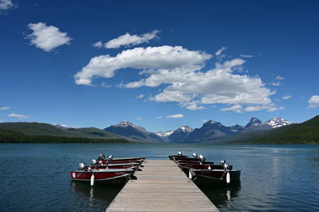 Apgar Village, Montana - 6-23-2022 - Rental outboard boats tied to dock in Lake McDonald in Glacier National Park under beautiful summer cloudscape.のeditorial素材