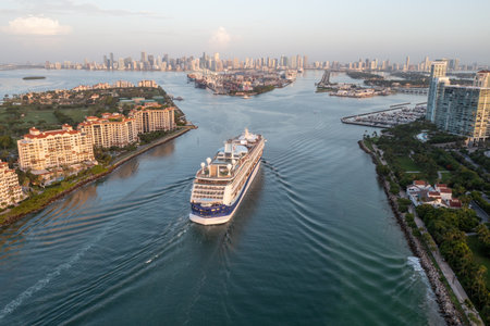 Miami Beach, Florida - July 22, 2023 - Cruise ship enters Port Miami at sunrise with Fisher Island, South Pointe Park and Miami skyline in background.のeditorial素材