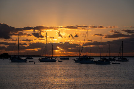 Sailboats anchored off Dinner Key in Miami, Florida under colorful sunrise cloudscape.の写真素材
