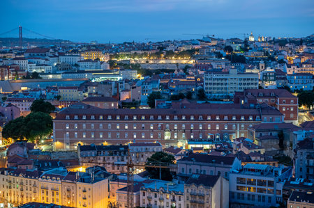 Illuminated buildings of Lisbon, Portugal in deep afternoon twilight with Tagus River and bridge in background from Miradouro da Senhora do Monte.の写真素材