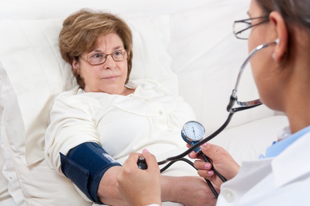 Sitting Doctor is measuring the Blood Pressure on a Senior Patientの写真素材