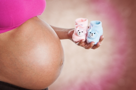Woman wondering if it is a boy or a girl, holding two small baby boots colored pink and blueの写真素材