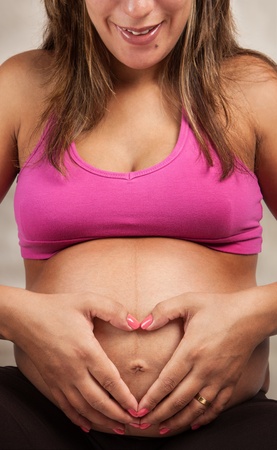 Pregnant Woman showing love making a Heart Shape over her baby inside bellyの写真素材