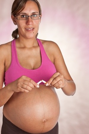 Pregnant Woman quits smoking and breaks her cigaretteの写真素材