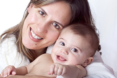 Mother holds baby in her arms, both face directly the camera smilingの写真素材