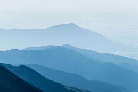 Telephoto view of distant blue toned mountain range arising from the plain below  Location  Piedmont, Italy の写真素材