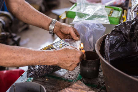Market vendor sealing bag of freshly roasted black coffee beans for sell in indonesian market...