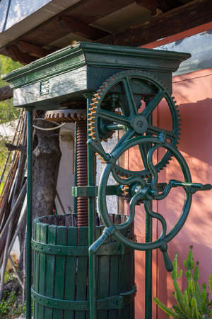 Vintage olive press, traditionally used to make oil in the mediterranean area, with his wooden barrel, green painted. Close up of the machinery. Liguria, Italy.の写真素材