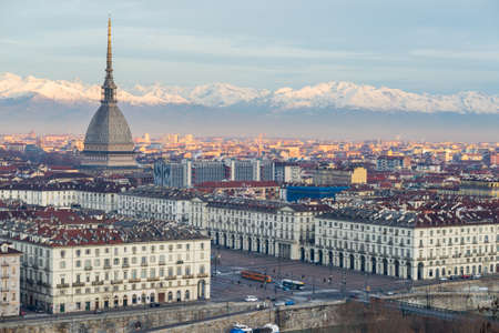 Torino (Turin, Italy): cityscape at sunrise with details of the Mole Antonelliana towering over the city. Scenic colorful light on the snowcapped Alps in the background.の写真素材