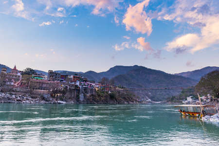 Cityscape of Rishikesh at sunset, holy town and travel destination in India. Colorful sky and clouds reflecting over the Ganges River.の写真素材