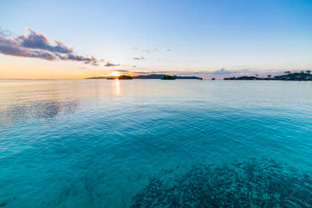 Togean Islands Sunrise, Togian Islands travel destination, Sulawesi, Indonesia. School of fish in...