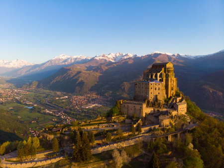 Aerial view old medieval abbey perched on mountain top, background snowy Alps at sunrise. Sacra di San Michele (italian) - Saint Michel Abbey (english traslation) - Turin, Italyの写真素材