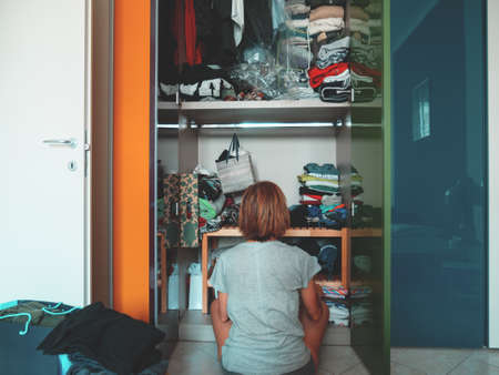 Woman looking at wardrobe, home interior, desperate housewife, cleaning home, rear view sitting, toned vintage style.の写真素材
