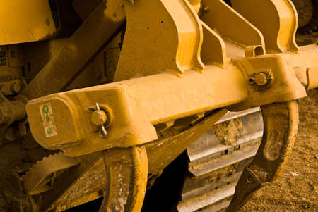 Excavator clamps and tracks covered in mud. Close up.