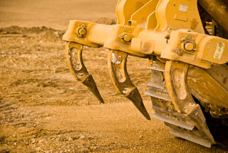 Excavator clamps and tracks covered in mud. Close up.