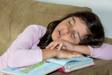 Girl sleeping over booksの写真素材