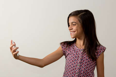 Girl taking a selfie, colored shirt, studio shot