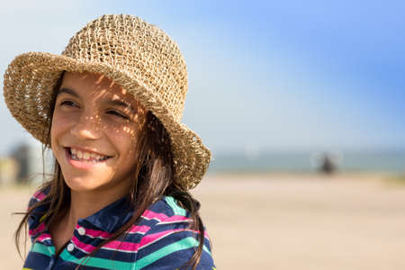 Young girl at beach with hat, blurry backgroundの写真素材