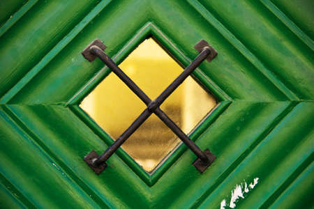 Little window with grid of a green wooden door