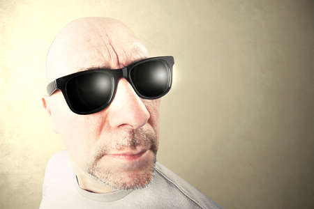 man with black sunglasses looking foward, beige background