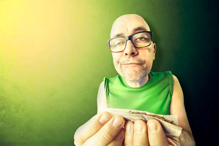 tossic and relaxed man rolling herb and tobacco