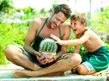 Young boy playing with his father in a green houseの写真素材