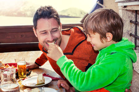 father and son having lunch in a chalet in the mountainの写真素材