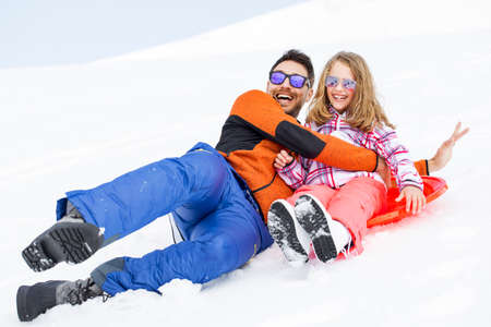 girl and his father sledding very fastの写真素材