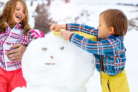 brother and sister  building a snowmanの写真素材