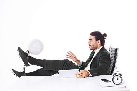Business man playing football in officeの写真素材