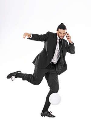 Business man kicking a ball while callingの写真素材