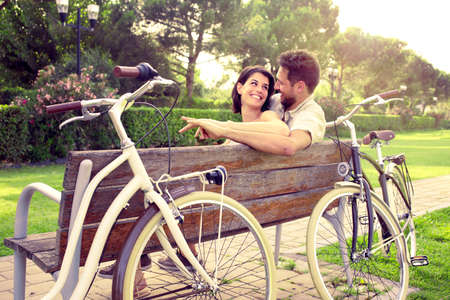 Couple in love sitted togheter on a bench with bikes besideの写真素材
