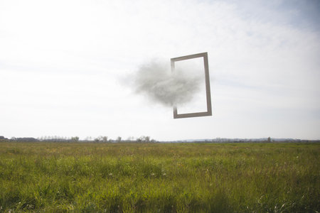 frame suspended between sky and earth crossed by a cloud, concept of freedomの写真素材