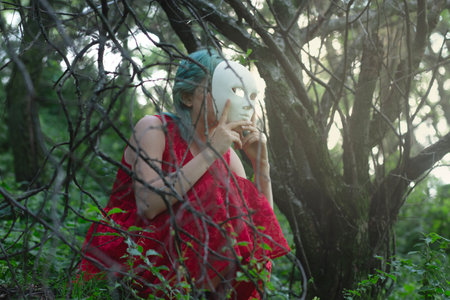 face of a woman hidden behind a white mask in a forestの写真素材